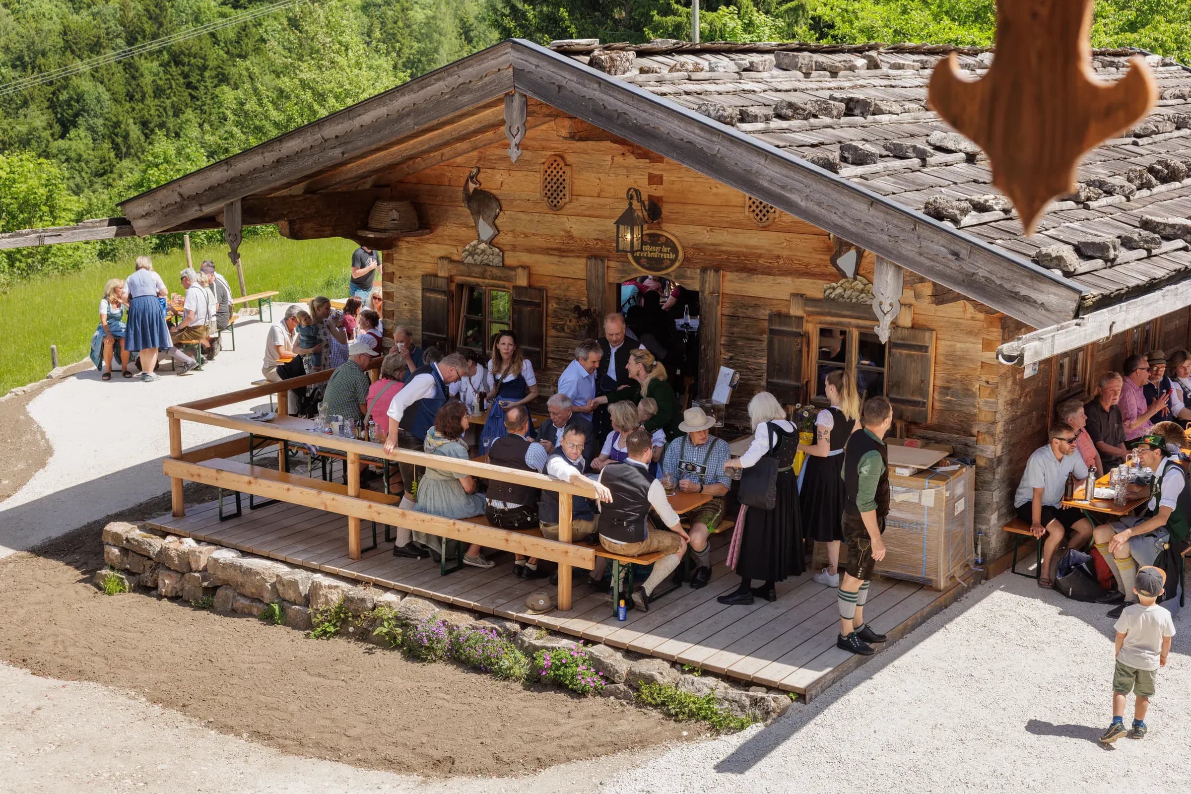 Feiernde Gaeste in Tracht auf der Terrasse des Berggasthofs Streichen